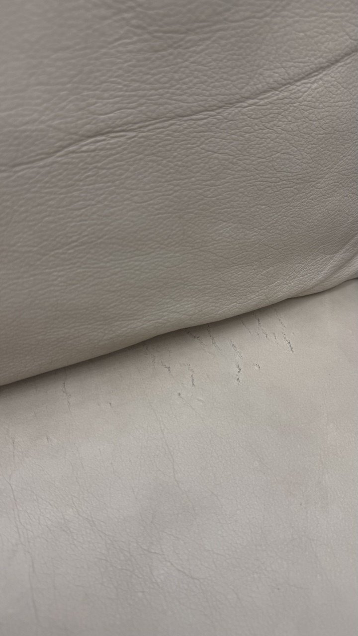 Cream leather cushion with surface scratches along the seam