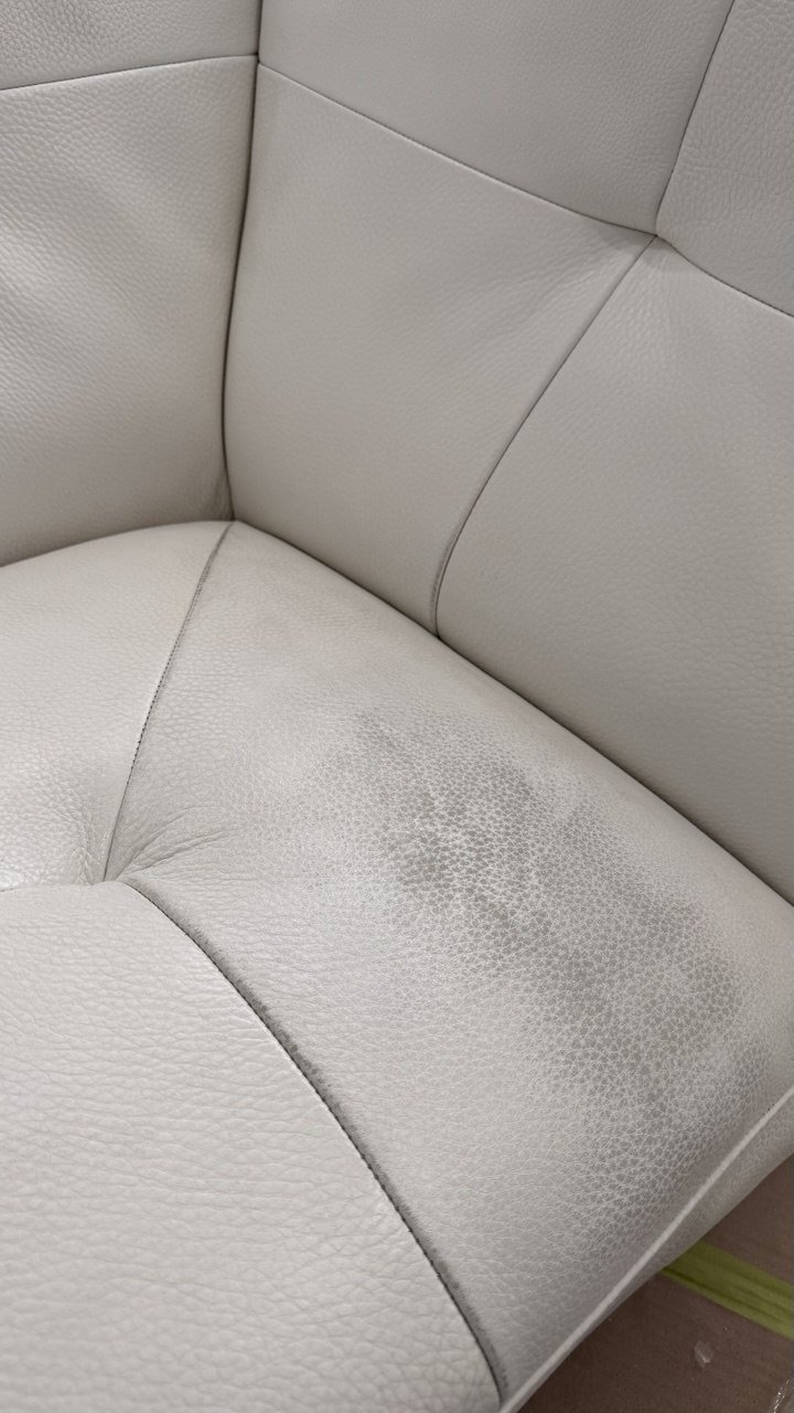 Cream leather seat corner with a faded, uneven patch
