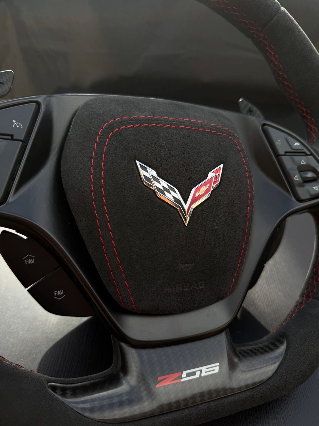 A Corvette Z06 steering wheel centre pad, rebuilt in black alcantara with red contrast stitching