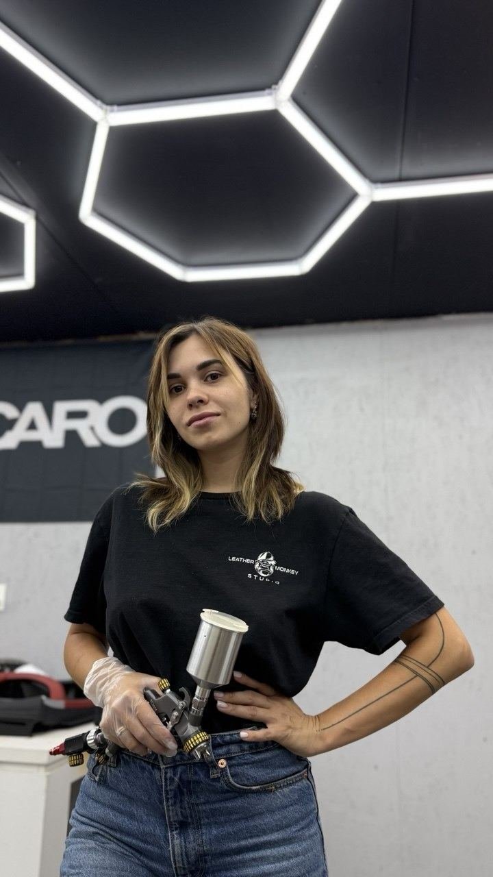 Valeri, arms crossed, holding a spray gun in the workshop